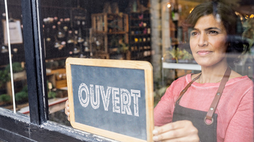 femme ouvrant sa boutique, retournant une pancarte d'ouverture