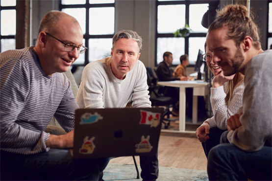 Frederic Lalonde, co-founder and CEO of Hopper, watching something on a laptop with fellow employees