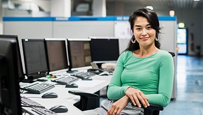 woman sitting in front of six screens on her desk