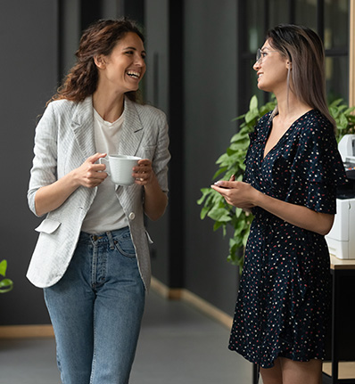 two women smiling and talking in an office