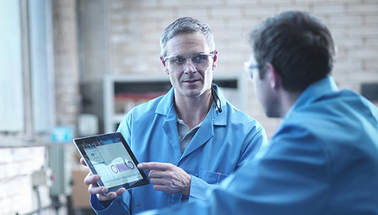 deux personnes en blouse de laboratoire regardant des graphiques sur une tablette
