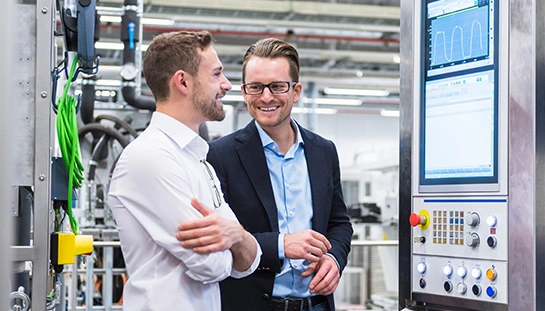 deux hommes d'affaires regardant une machine dans une usine