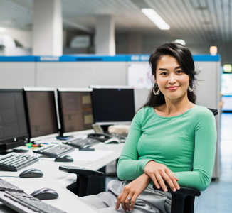 woman smiling in front of several computer screens