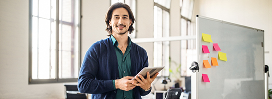homme portant un cardigan bleu tenant une tablette dans son bureau de studio