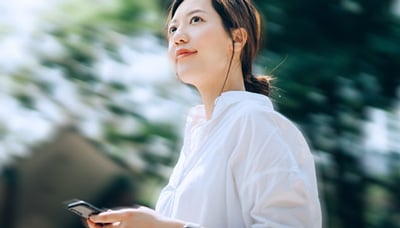 Woman walking in a park with her cellphone in hand