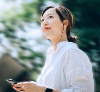 Asian woman walking in a park with her cellphone in hand