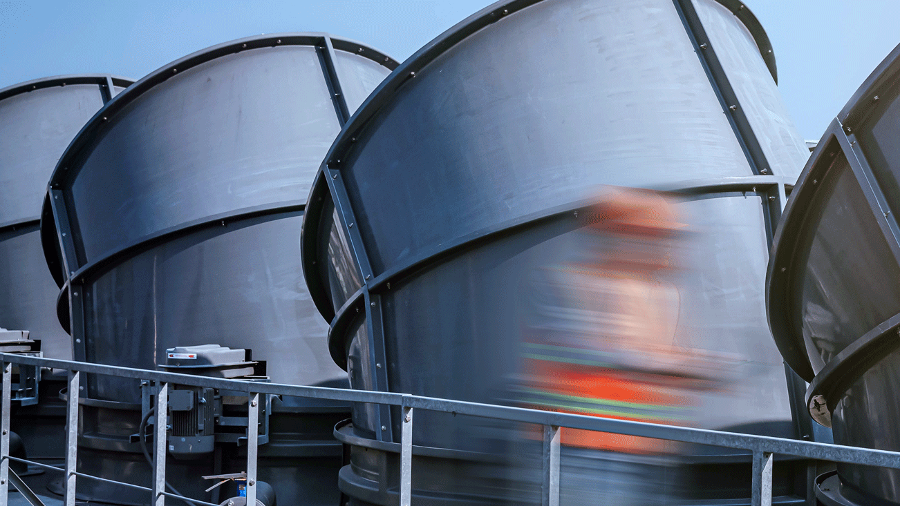 Worker with an orange jacket walking on industrial building roof 