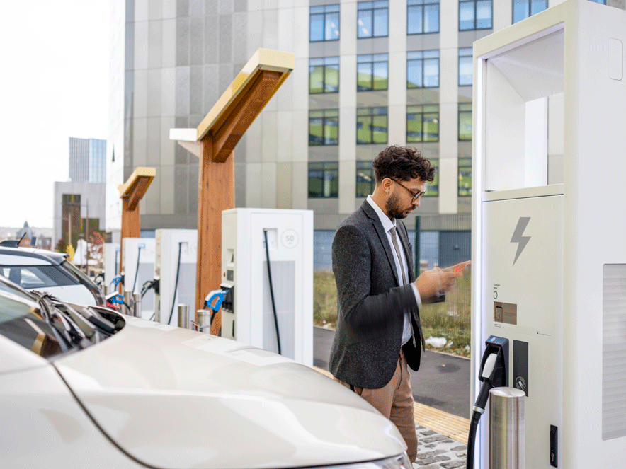 Men looking his cell phone to charge his car near a building