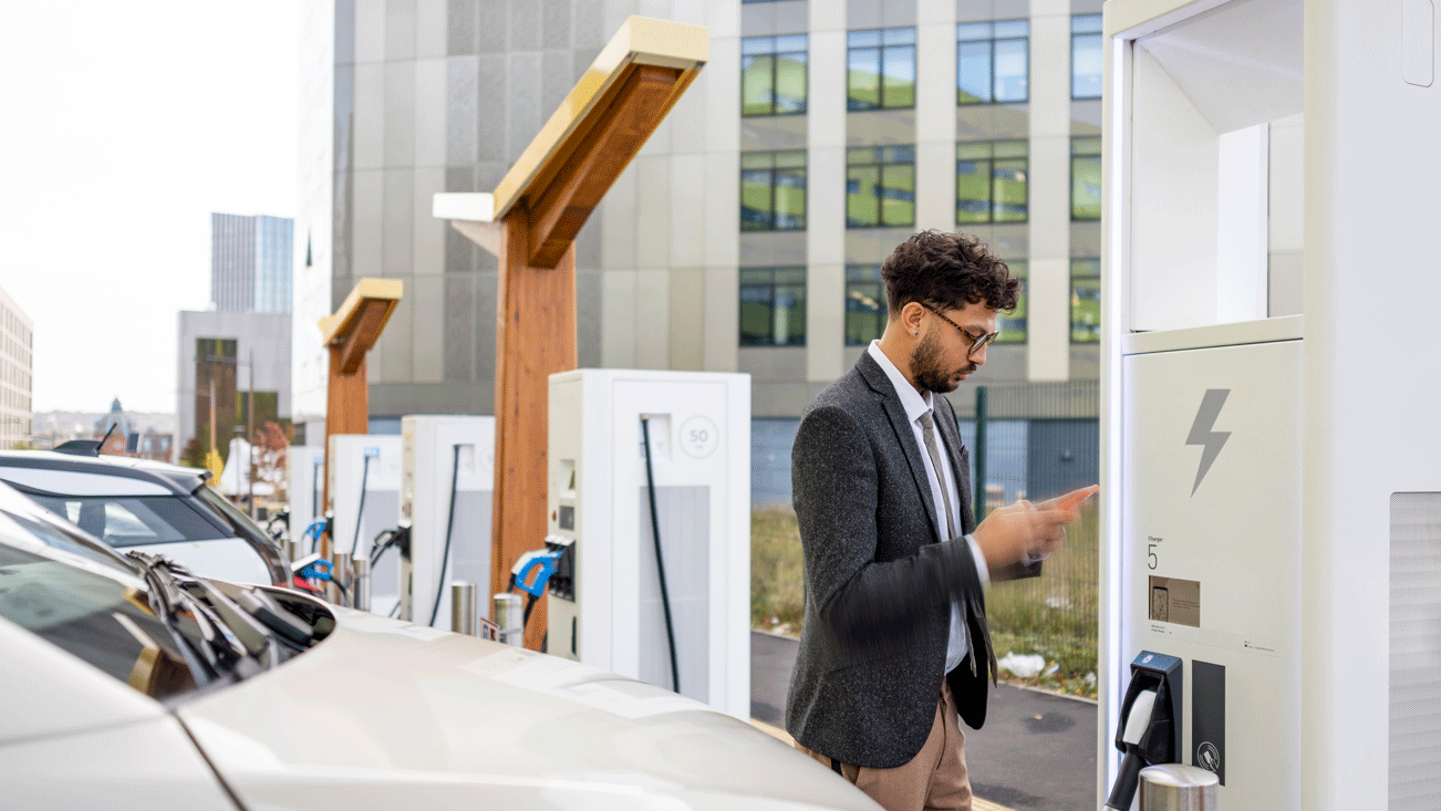 Men looking his cell phone to charge his car near a building