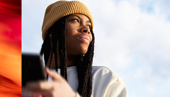 Black women with yellow hat looking away, sky background