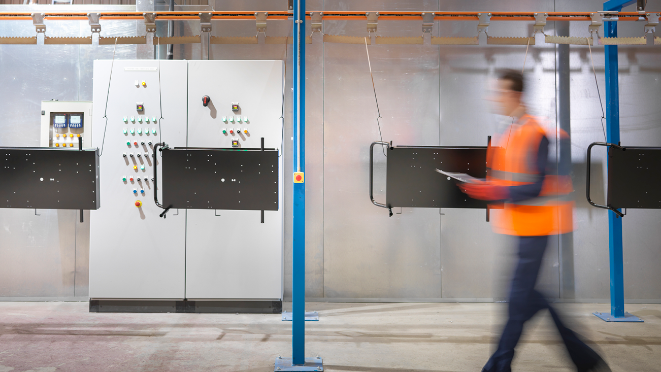 men walking in maintenance room in cement, with an orange jacket