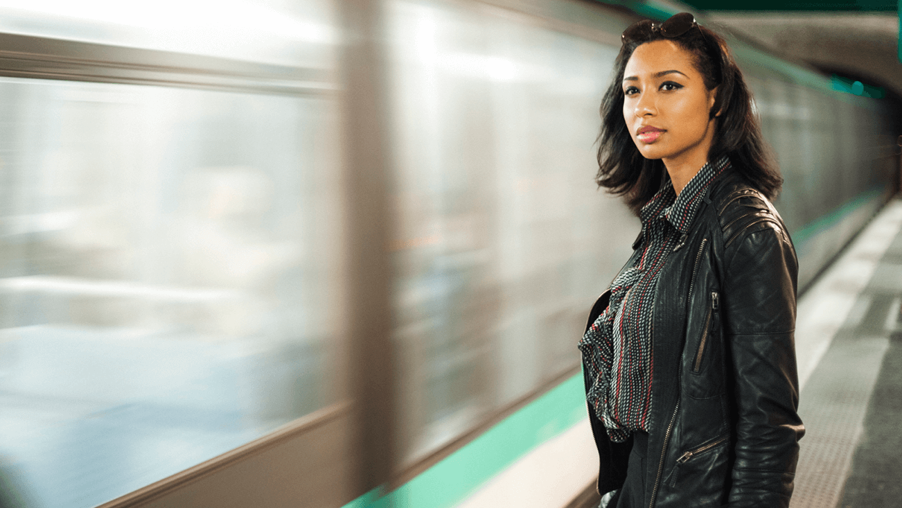 woman next to a subway, watching as it passes by