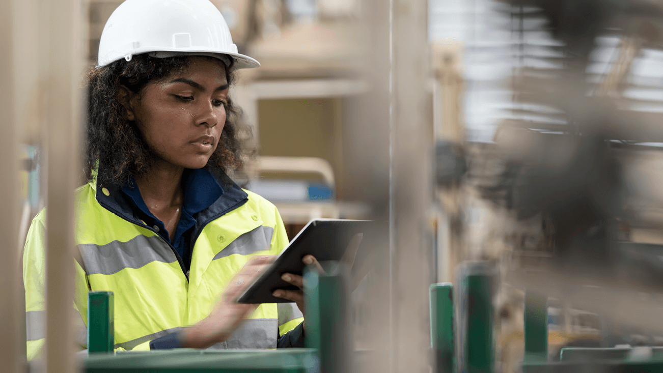 woman with white helmet and yellow jacket in a factory