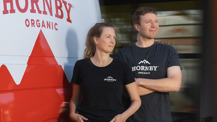 White man and woman posing outside in front of their truck