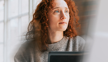 redhead dreamer woman sitting at desk with computer