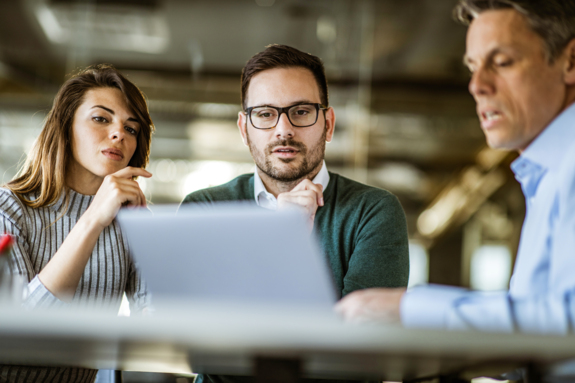 Young couple and real estate agent using laptop in a meeting