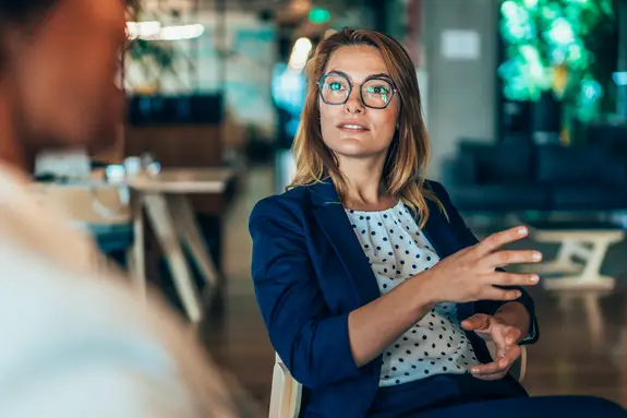 Femme d'affaires d'âge moyen en conversation avec un collègue.