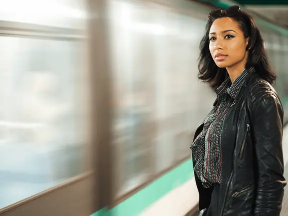 femme à côté d'un métro, le regardant passer