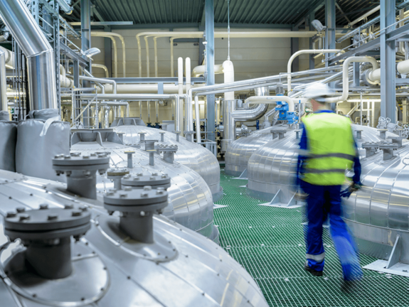 homme avec veste jaune et casque blanc, marchant dans une usine