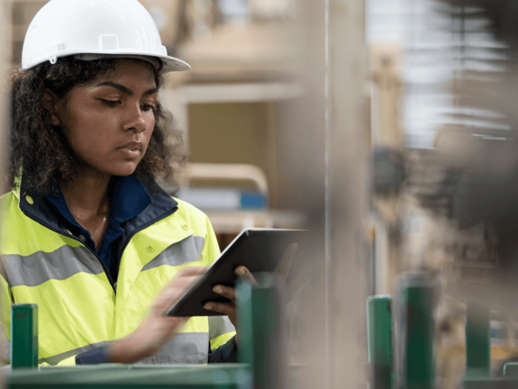 femme avec casque blanc et veste jaune dans une usine