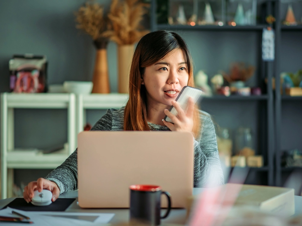 woman sitting in front of laptop negociating on her phone