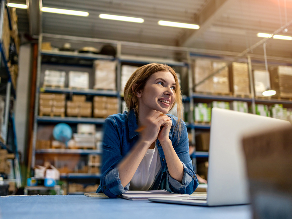 young woman working in a warehouse on a laptop