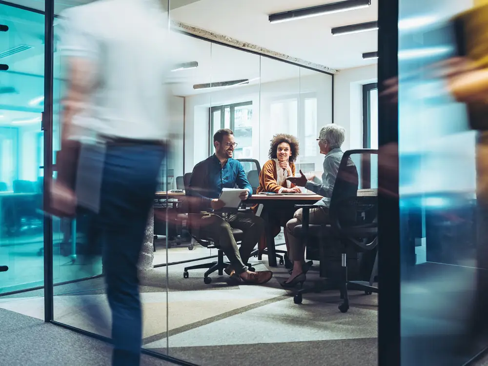Group of business persons having a meeting in a closed glass conference room