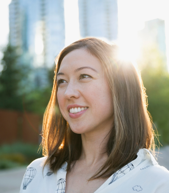 young woman smiling, the sun shines behind her