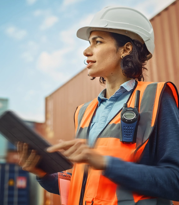 Woman on export site with helmet, tablet and an orange vest