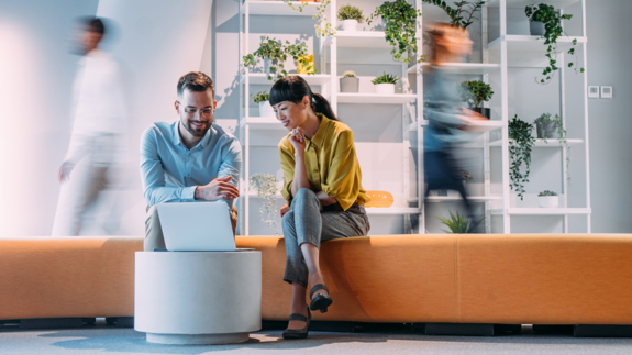 man and woman colleagues sitting and looking at a laptop