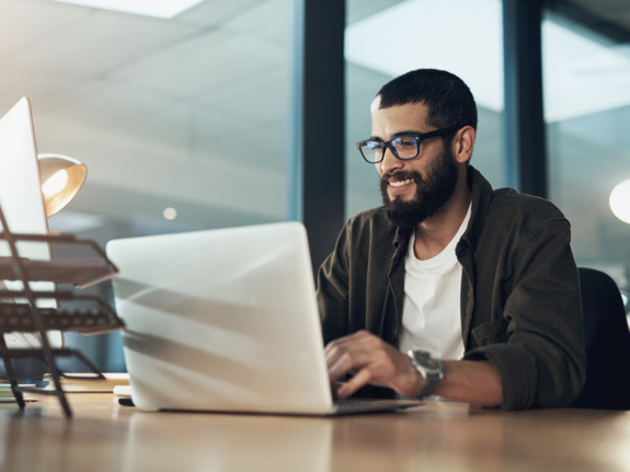 young stylish entrepreneur working on his laptop and smiling