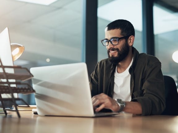 young stylish entrepreneur working on his laptop and smiling
