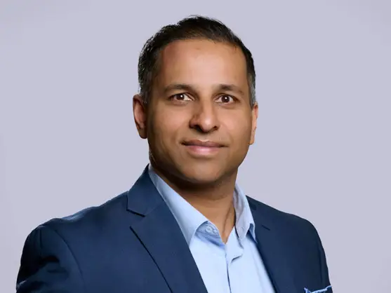 Portrait of BDC employee Ronnie Prasad wearing a blue suit and shirt
