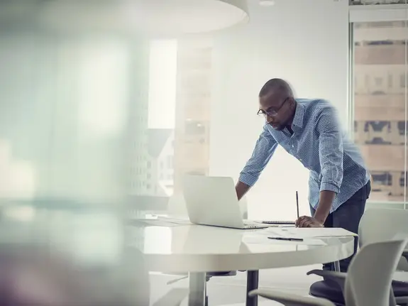 homme d'affaires noir travaillant dans un bureau bien éclairé sur un ordinateur